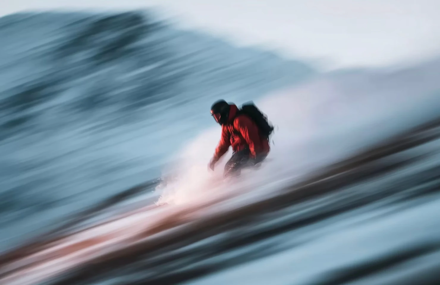 A snowboarder moving quickly down a snowy slope